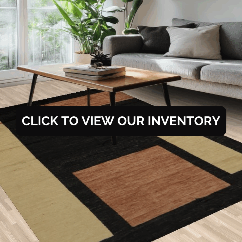 A contemporary living room with a gray sofa, large green plant, and a wooden coffee table on a modern rug with tan, black, and rust-colored geometric blocks.