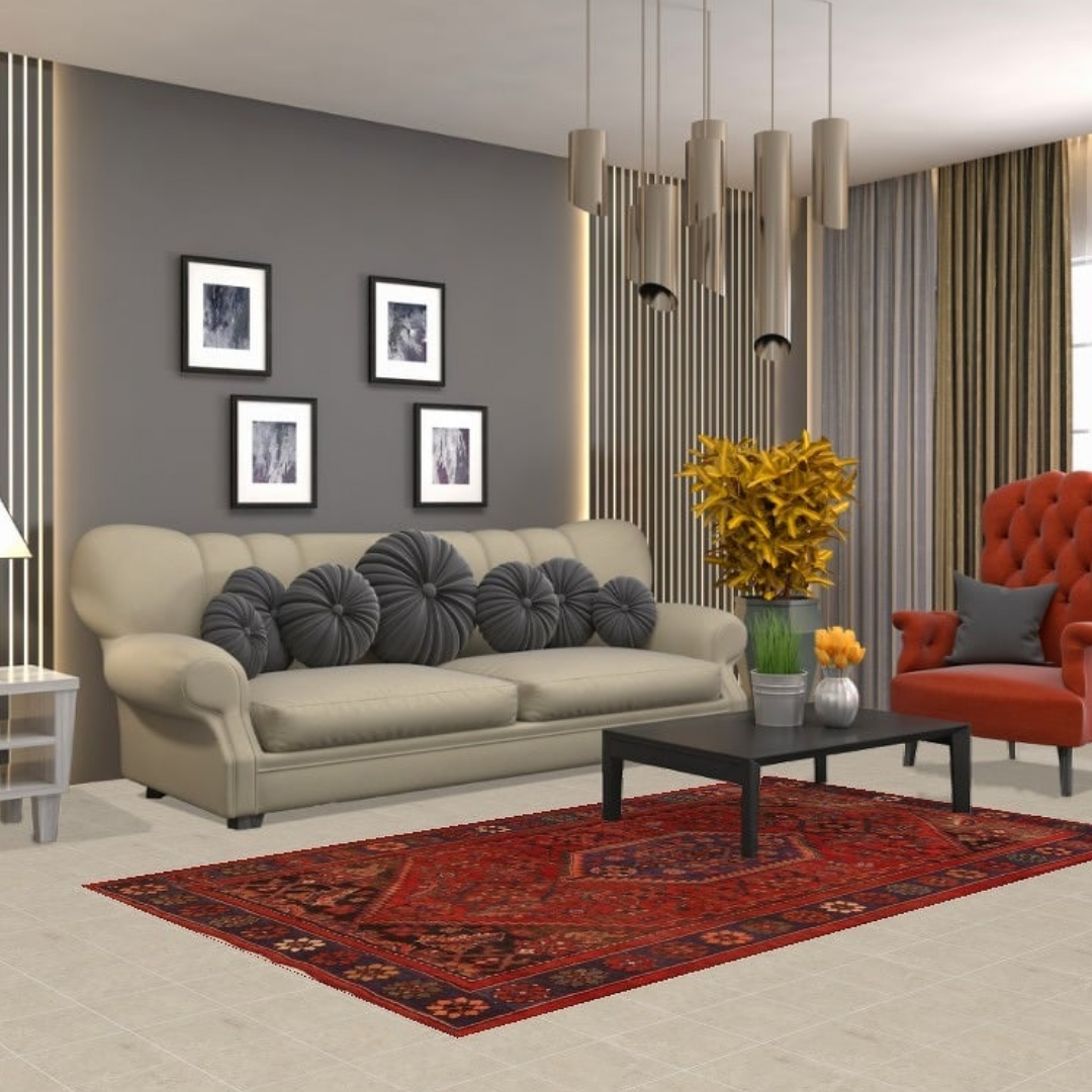 A stylish living room with a gray accent wall, beige sofa with round gray pillows, and an orange armchair. A red patterned area rug adds warmth beneath a black coffee table and modern pendant lights.