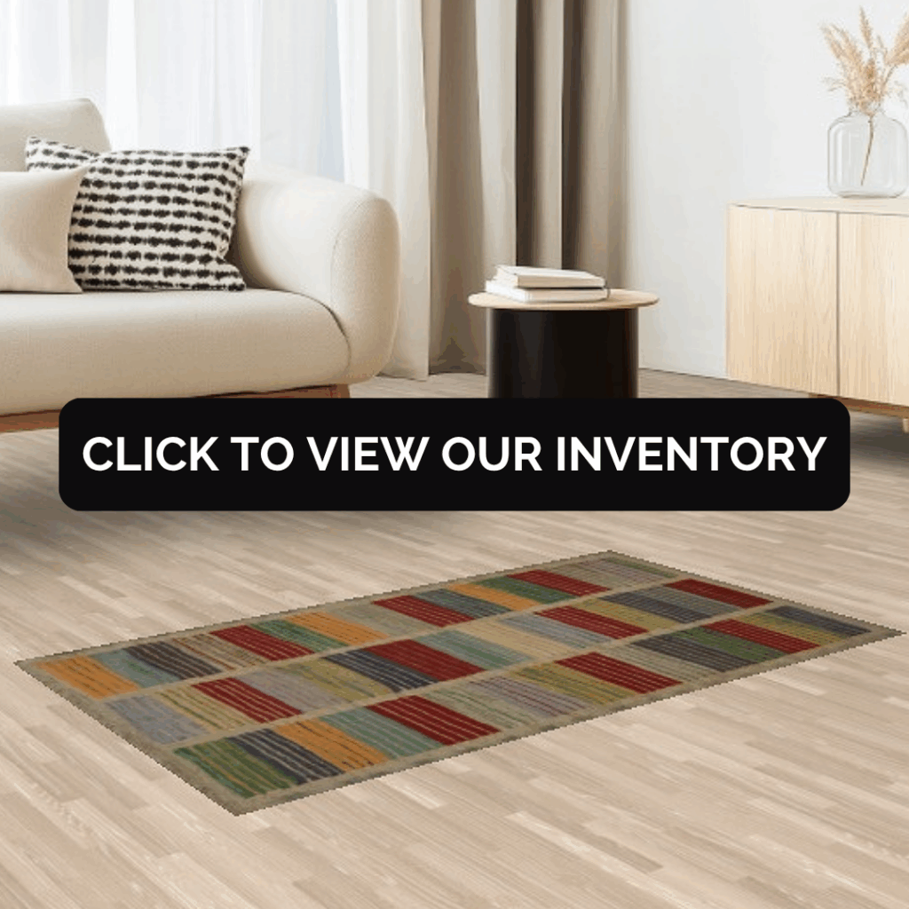A modern living room with a light beige sofa, a black-and-white patterned pillow, and a colorful geometric rug featuring red, green, yellow, and blue rectangles. A black side table holds books beside a light wood console.