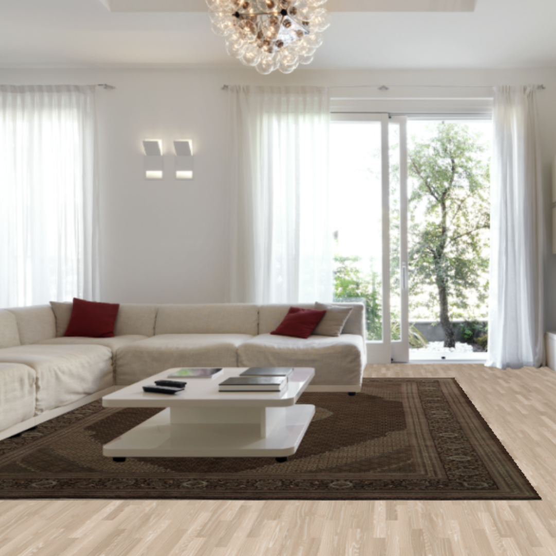 A sunlit living room with floor-to-ceiling curtains, a beige sectional sofa, and a glossy white coffee table on a dark brown area rug. The soft natural light and minimalist design create a calm, elegant atmosphere.
